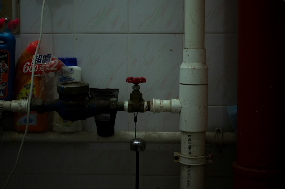 Indoor supply pipe with a water meter and a red-handled shut-off valve