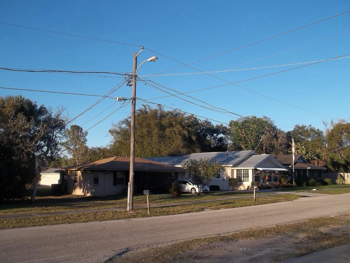 Single-story homes with shingle and metal roofs on a street in old Lutz