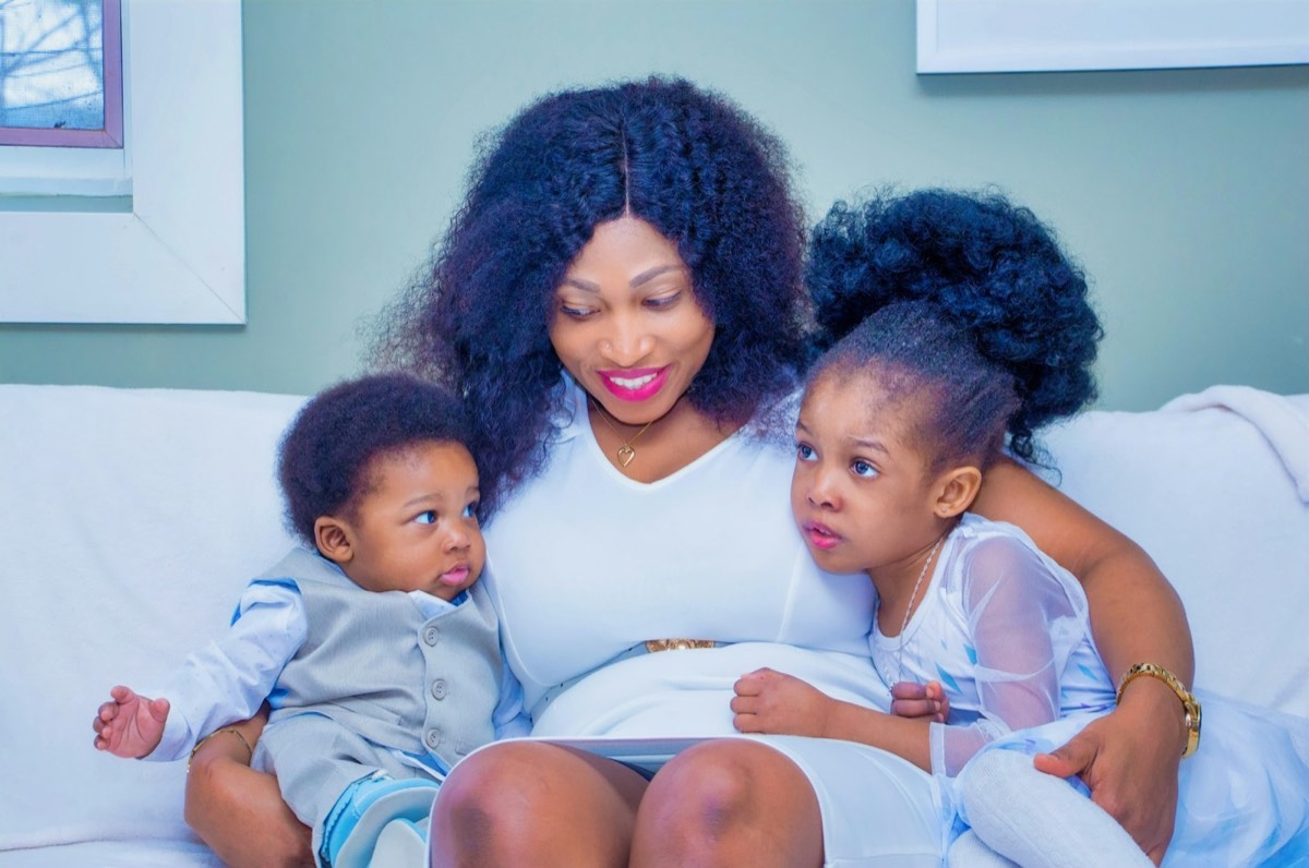Smiling mother on a white couch with her toddler son and young daughter