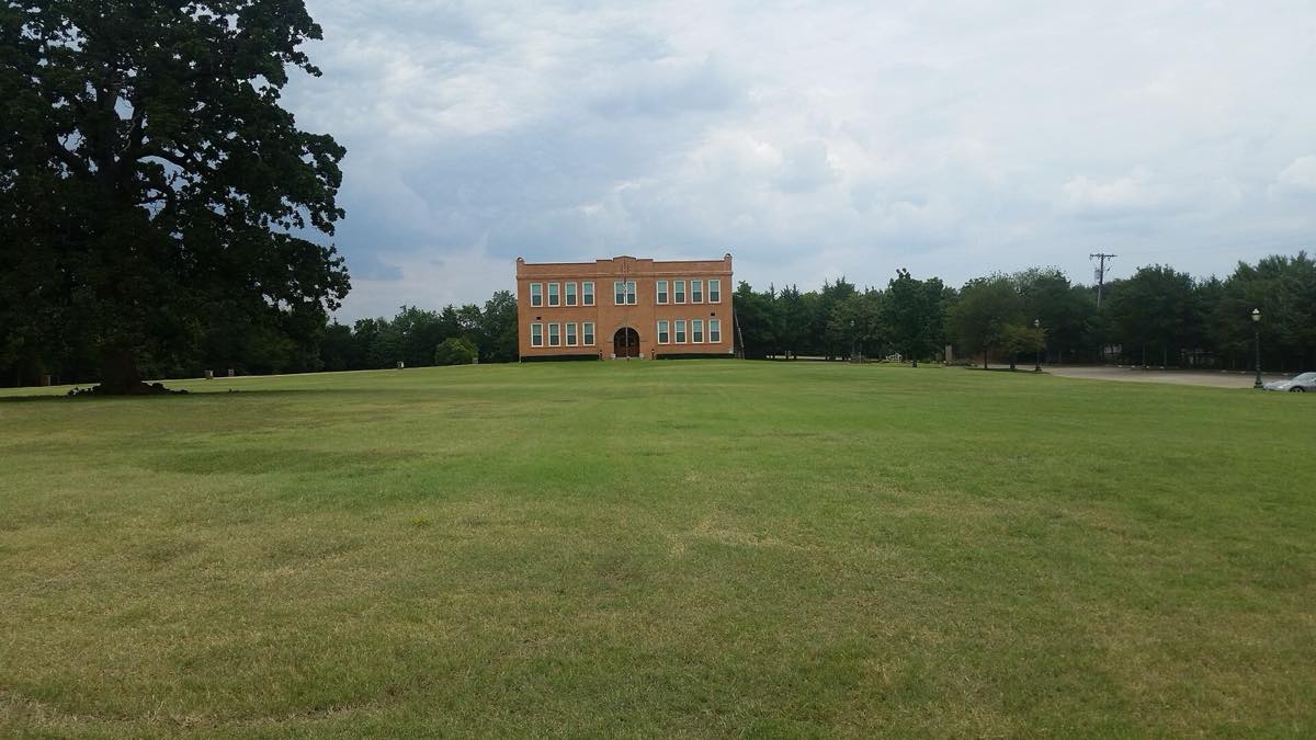 Open lawn stretching back to the Old Bedford School, Bedford, TX, with trees at the edges
