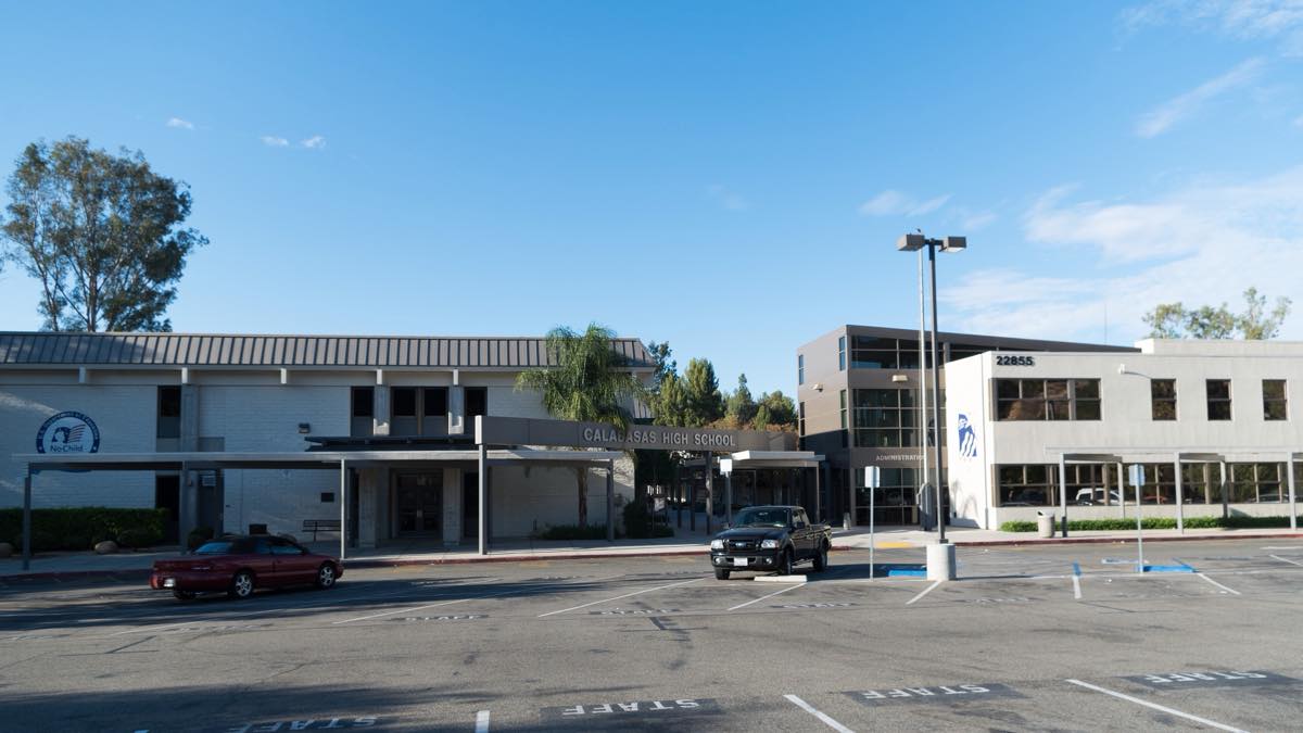 Calabasas High School buildings and front parking lot on Mulholland Highway under a clear sky