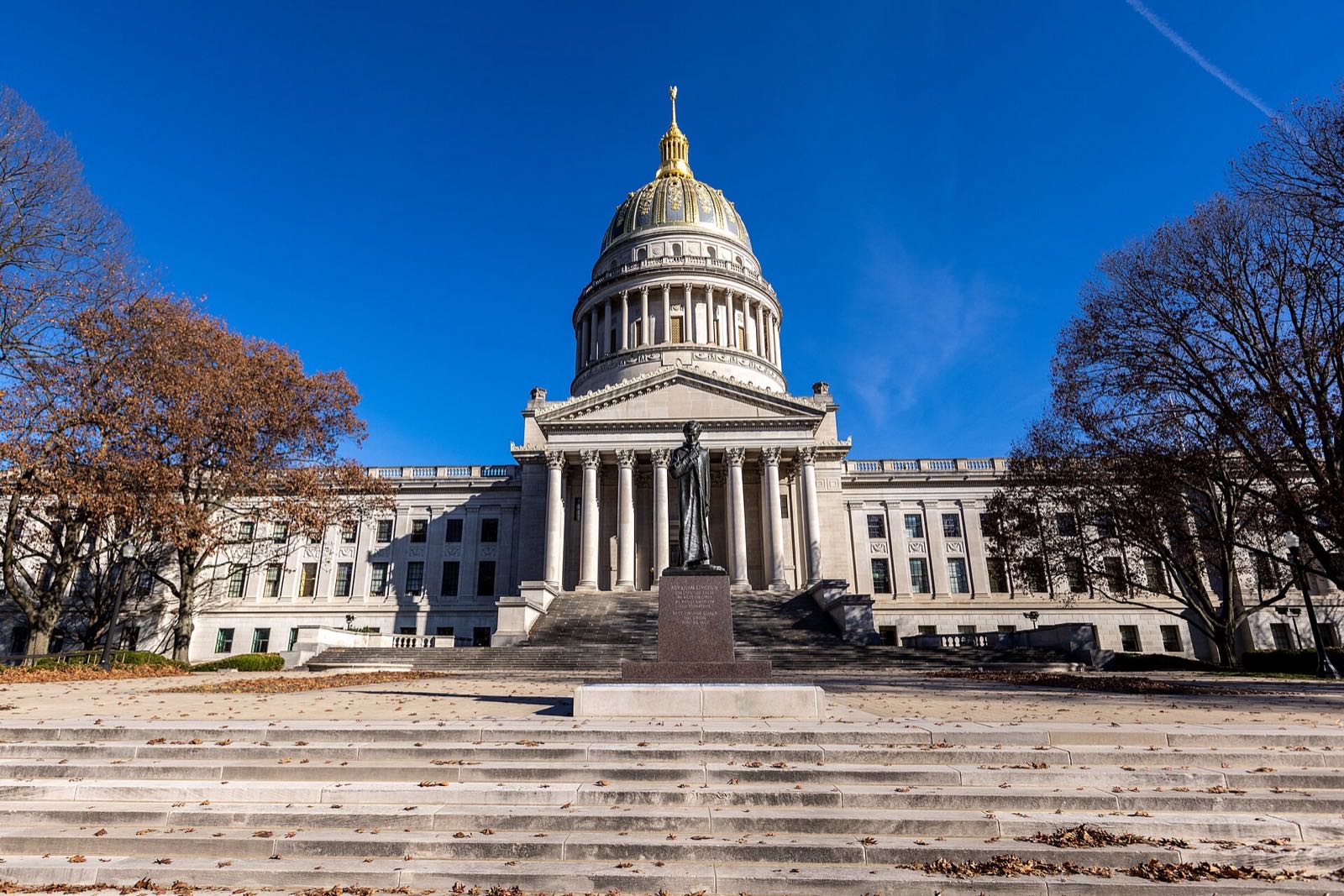 West Virginia State Capitol and its gold dome in Charleston under a clear blue sky, seen from the front steps