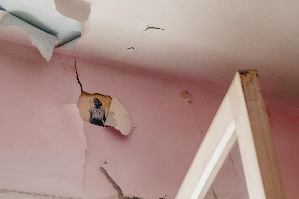 Cracked, peeling plaster and paint on a pink ceiling and wall, the kind of damage a slow leak leaves behind