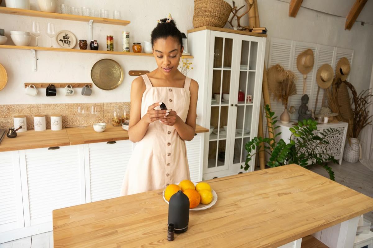 A woman standing at a wooden kitchen island, looking down at something in her hands