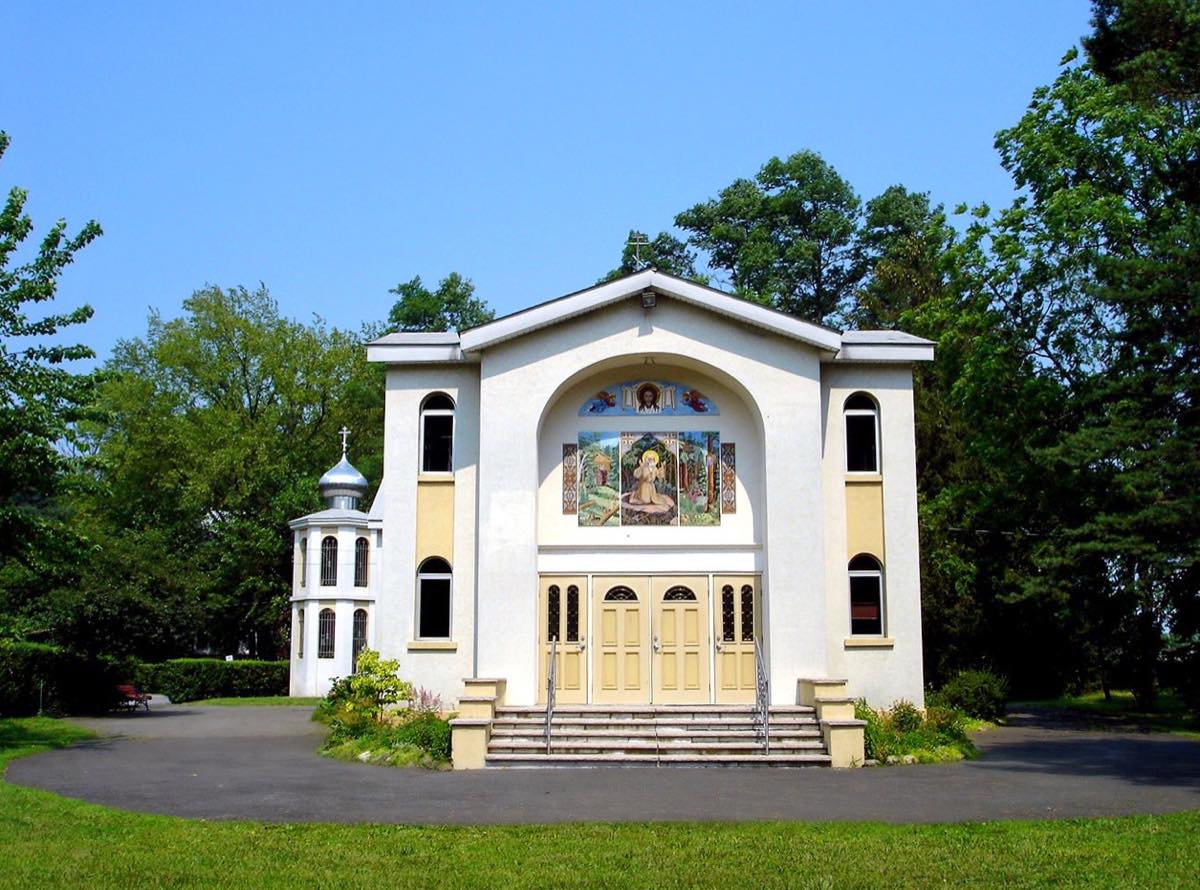 White church at the Novo-Diveevo convent with its icon mosaic facade and small domed bell tower