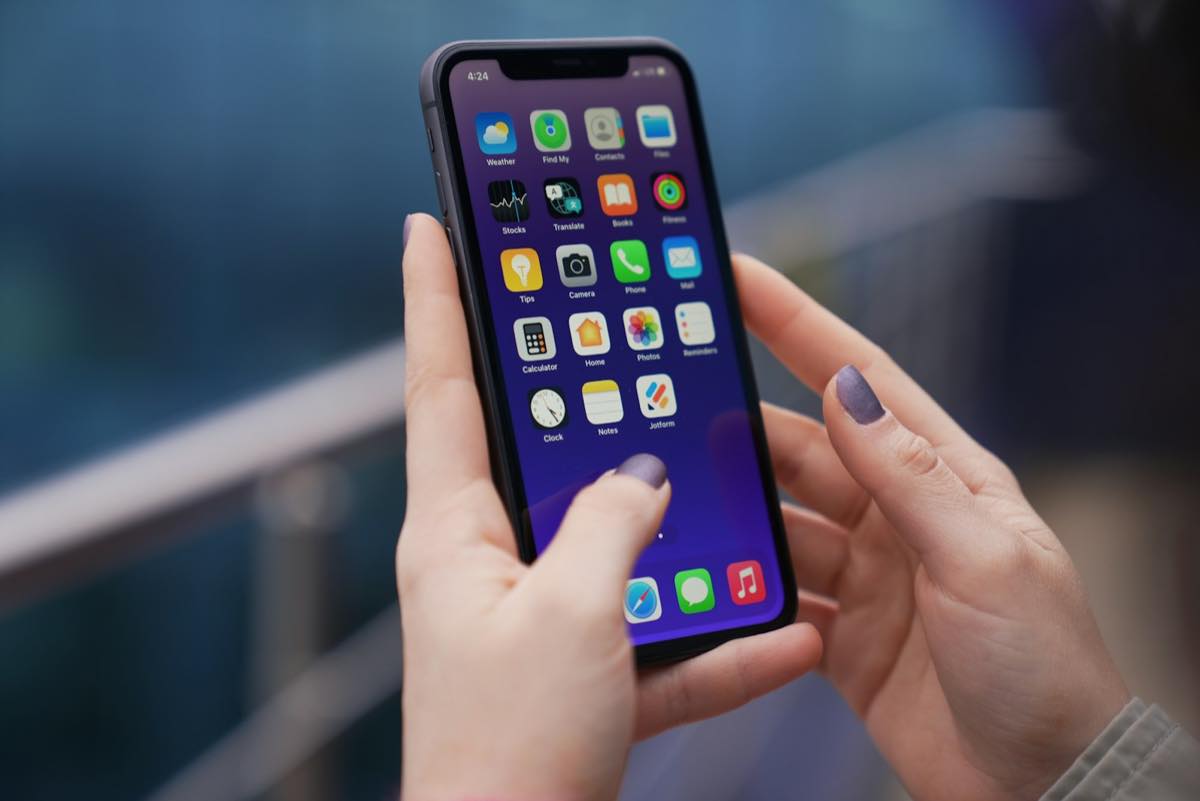 Close-up of a woman's hands holding a smartphone, thumb over the home screen