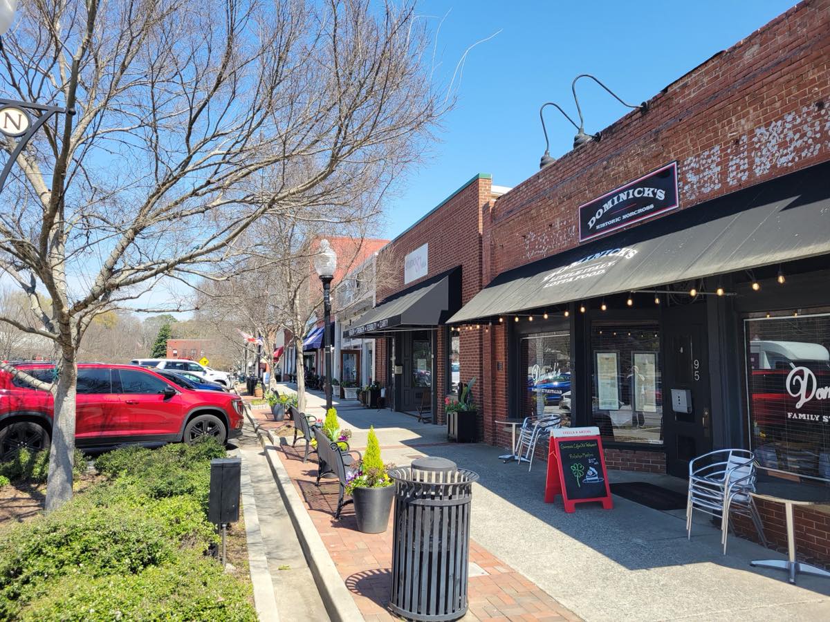 Historic brick storefronts and sidewalk cafe tables on South Peachtree Street in downtown Norcross