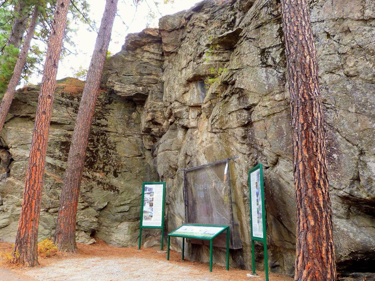 The granite cliff at Treaty Rock Historic Site with its interpretive signs among ponderosa pines