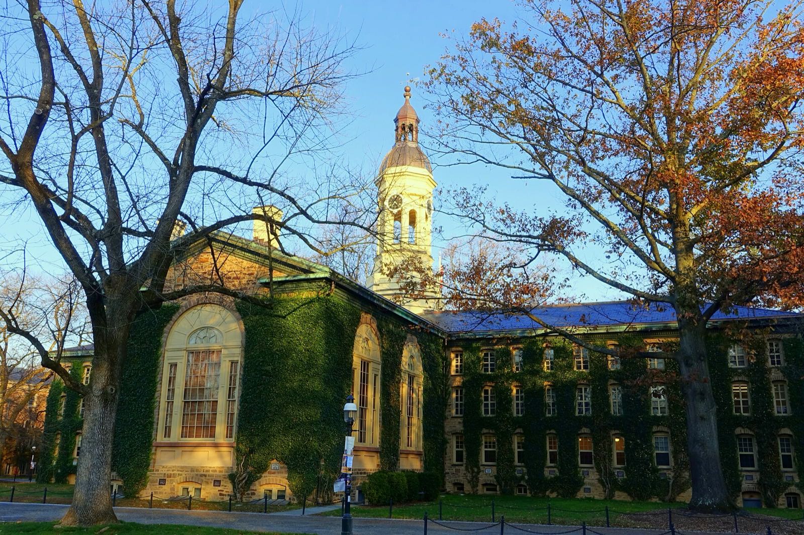 Nassau Hall and its cupola on the Princeton University campus under a clear blue sky with autumn trees