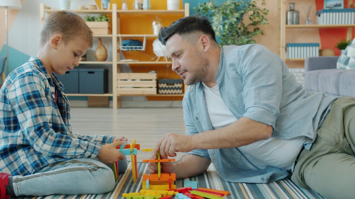 Father and son building with colorful blocks on the living-room floor