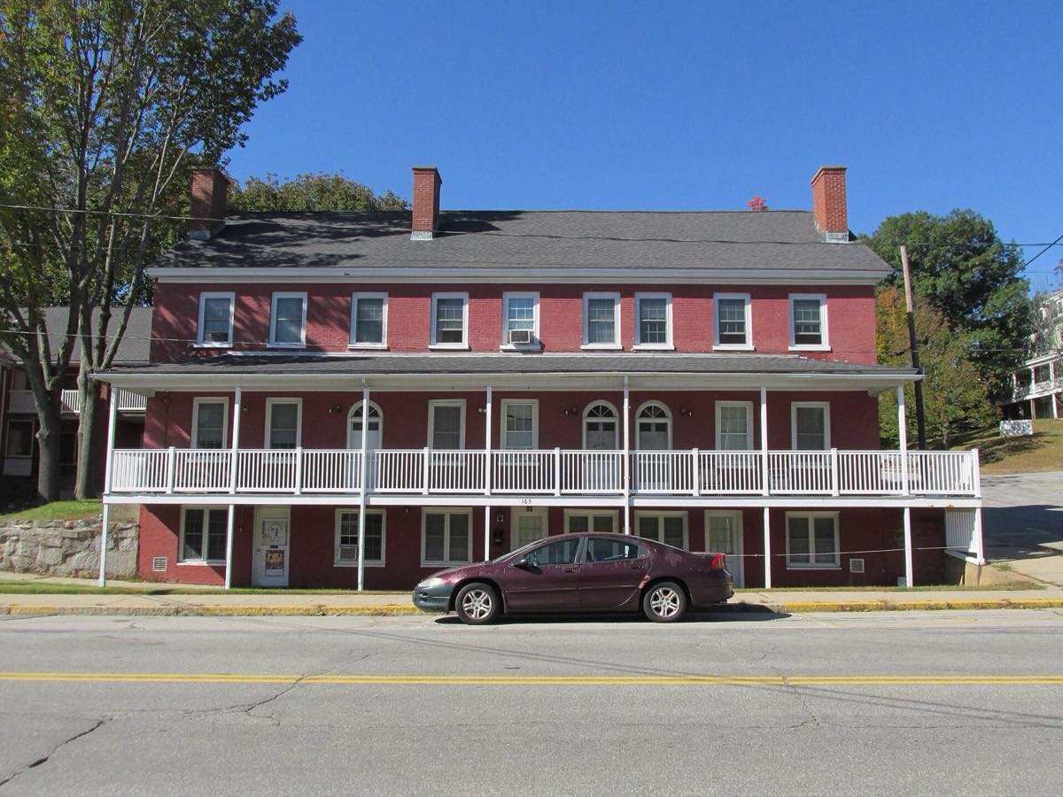 163 Main Street downtown Somersworth: a long red three-story building with a white two-level porch