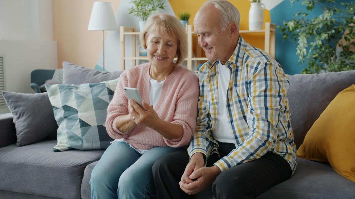 Older couple on the sofa looking at a smartphone together