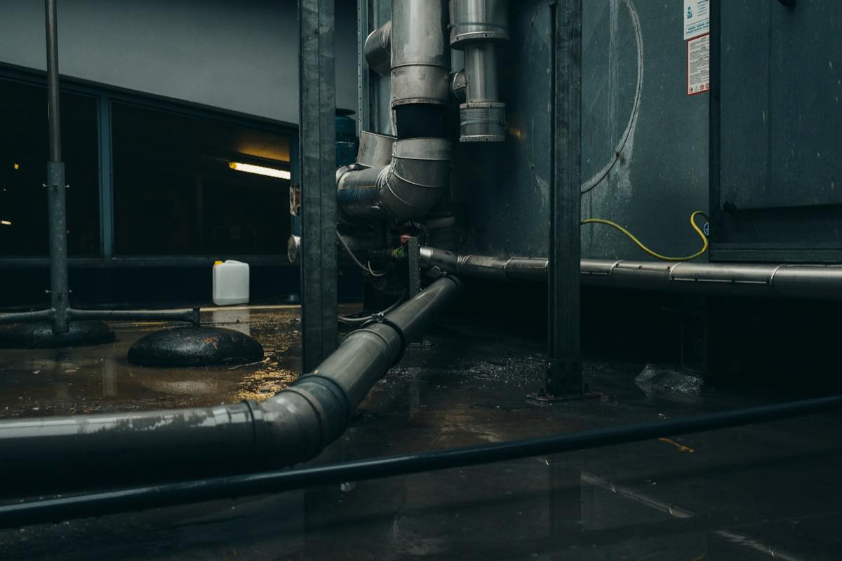 Water pooled on a utility room floor around pipes and fittings